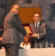 Lic. Alfredo Paredes, coordinador general y director de la ASCA recibe la placa de reconocimiento que le acredita al IDAC-ASCA como el stand más creativo de la feria. Entrega licenciado José R. Lantigua, Ministro de Cultura.